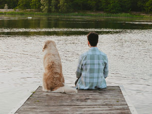 A dog and a man sit on a dock